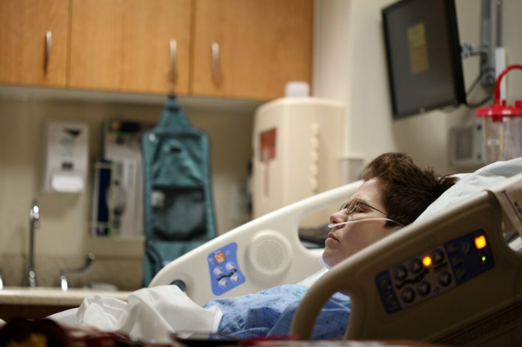 Person lying on a hospital bed recovering from illness