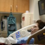 Person lying on a hospital bed recovering from illness