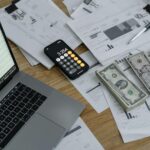 A calculator beside stacks of cash on a table.