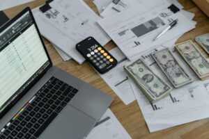 A calculator beside stacks of cash on a table.