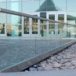 A glass railing adjacent to a modern building, enhancing safety and aesthetic appeal.