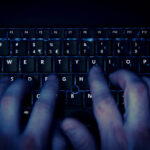 hands typing on keyboard in blue light with motion blur