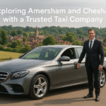 Silver Mercedes-Benz taxi parked on a quiet street in Amersham, with a professional driver standing nearby, charming townhouses in the background, soft daylight.