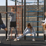 Students in colleges with athletic training programs stretching outdoors at college campus