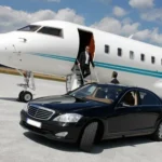 Luxury black limousine waiting beside a private jet on an airport runway, chauffeur assisting a business traveler arriving from the plane.