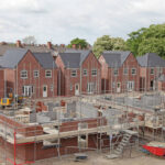 Ongoing residential building project with red brick homes and scaffolding, illustrating factors that influence house construction cost in the uk.
