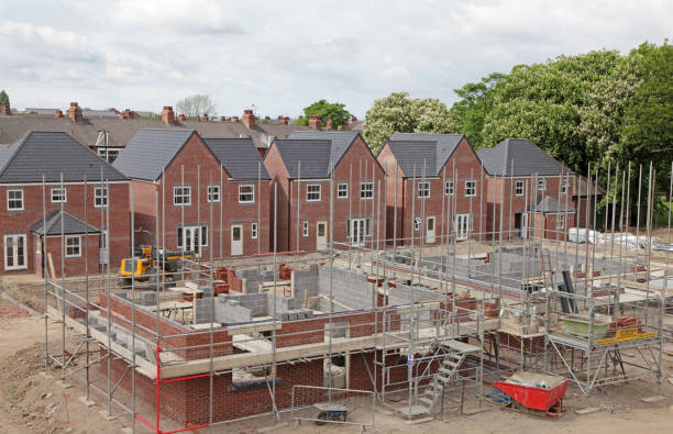 Ongoing residential building project with red brick homes and scaffolding, illustrating factors that influence house construction cost in the uk.