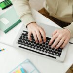 Student typing on a laptop with a calculator and technical books nearby, utilizing Electrical Engineering Assignment Help services.