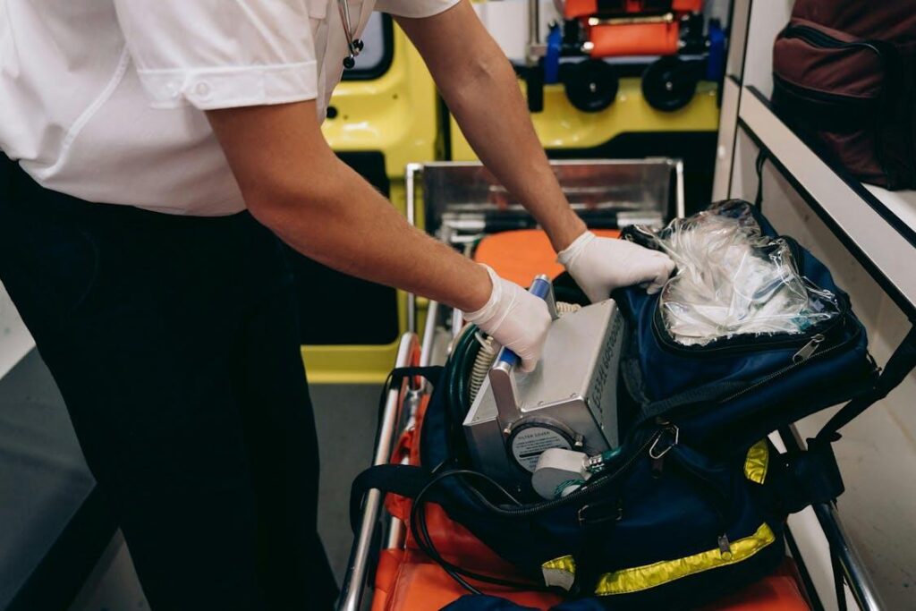 Paramedic standing over an open medical bag while organizing emergency equipment before patient care