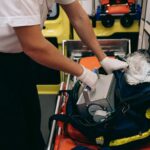 Paramedic standing over an open medical bag while organizing emergency equipment before patient care