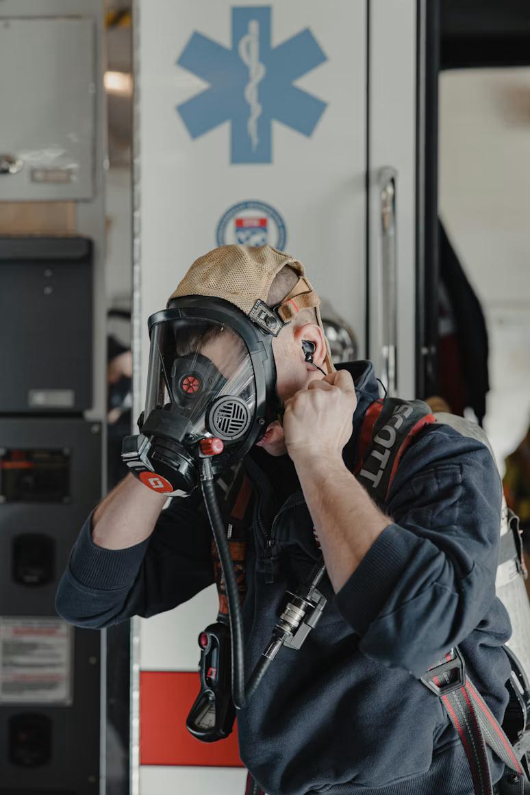 EMT wearing a gas mask and approaching a potentially hazardous scene cautiously