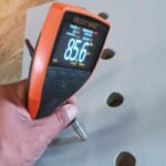 Technician using a digital thickness gauge to measure a metal surface