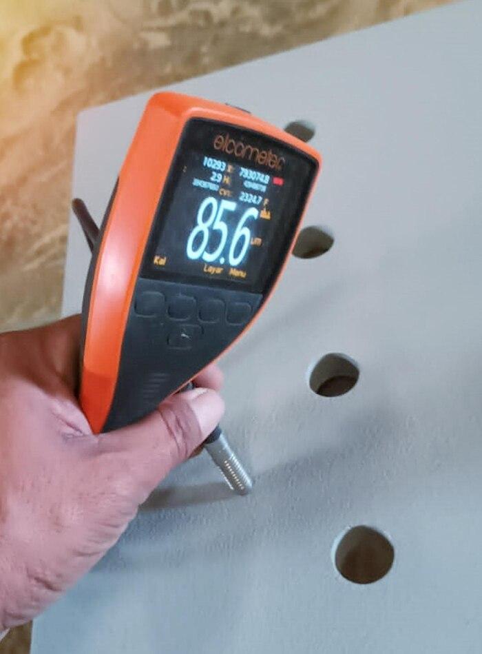 Technician using a digital thickness gauge to measure a metal surface