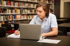 good-looking-college-student-taking-notes-using-laptop-library (1)