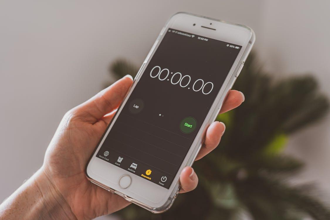 Person timing their study session with a smartphone stopwatch to practice NREMT pacing