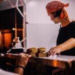 Food service worker placing freshly prepared burgers and sandwiches on a restaurant counter for customers