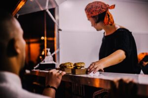 Food service worker placing freshly prepared burgers and sandwiches on a restaurant counter for customers