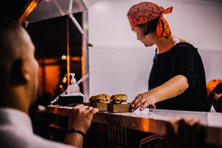 Food service worker placing freshly prepared burgers and sandwiches on a restaurant counter for customers
