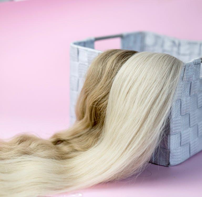 Two sets of wigs placed in a basket.