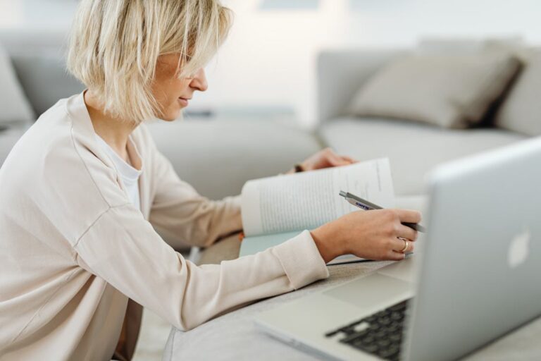 Woman studying NREMT exam questions at home using a laptop and textbook