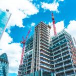 A wide-angle view of a high-rise building under development in the City of London, showcasing the technical phases of shell & core construction UK amidst iconic landmarks like The Gherkin.