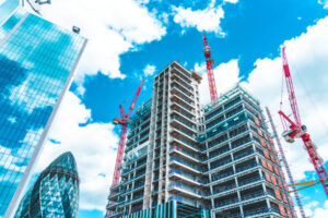 A wide-angle view of a high-rise building under development in the City of London, showcasing the technical phases of shell & core construction UK amidst iconic landmarks like The Gherkin.