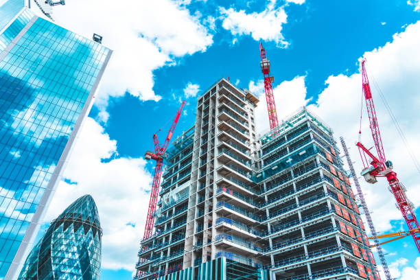 A wide-angle view of a high-rise building under development in the City of London, showcasing the technical phases of shell & core construction UK amidst iconic landmarks like The Gherkin.