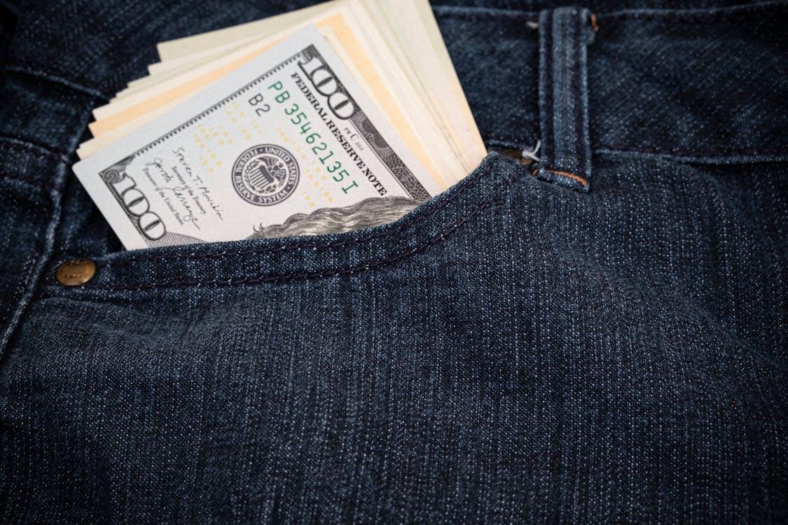 Several 100 US dollar bills visible in the pocket of jeans, representing recovered funds from subrogation and insurance claims