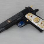 Black customized firearm featuring gold and silver decorative accents with detailed engraving work
