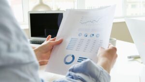 Person holding printed papers showing financial data for insurance analysis