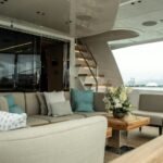 The pristine outdoor lounging deck of a luxury yacht featuring spotless cream cushions, polished accents, and immaculate teak detailing under a sun-drenched sky