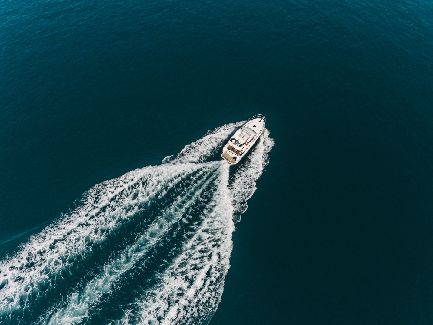 A premium motor yacht cruising at high speed through deep blue ocean waters