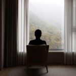 A silhouette of a man looking outside a window