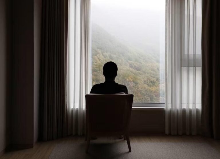 A silhouette of a man looking outside a window