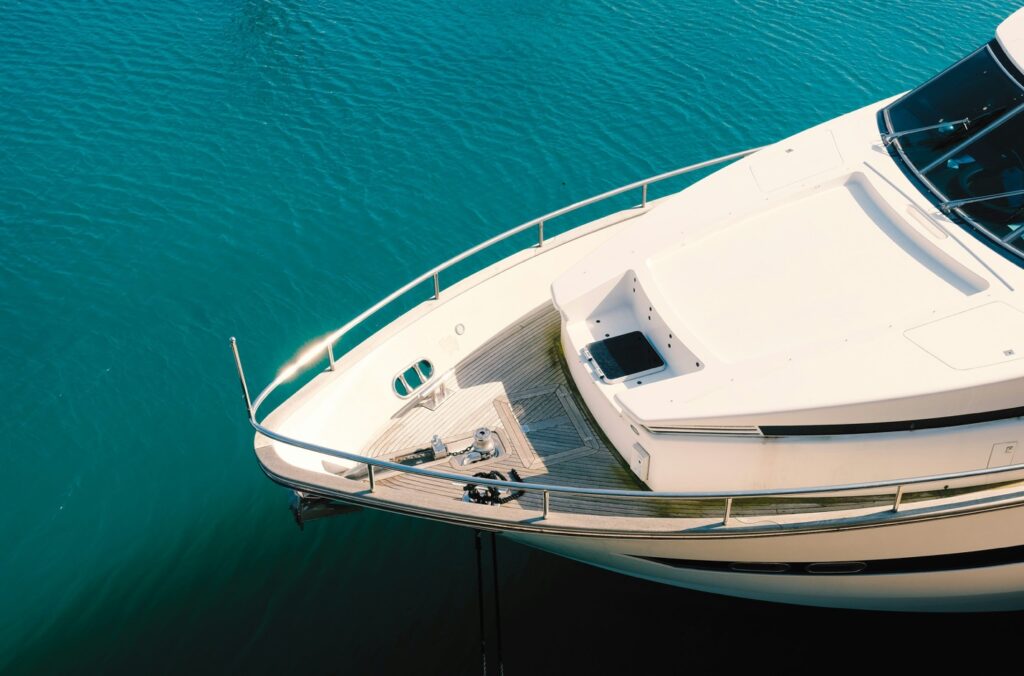 A premium motor yacht anchoring in calm, pristine blue waters along the Palm Beach coastline, displaying a flawless finish and highly reflective hull
