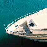 A premium motor yacht anchoring in calm, pristine blue waters along the Palm Beach coastline, displaying a flawless finish and highly reflective hull