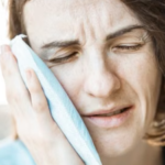 Woman applying a cold compress to her cheek for relief from toothache pain