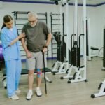 imgi_21_wide-shot-professional-rehab-coach-helping-elderly-patient-with-taped-knee-walk-with-cane_249974-29065