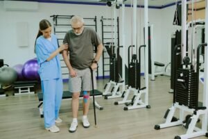 imgi_21_wide-shot-professional-rehab-coach-helping-elderly-patient-with-taped-knee-walk-with-cane_249974-29065