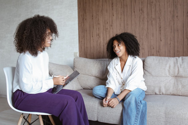two women sitting on a couch and having a conversation.