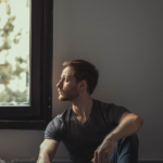 man sitting by a window reflecting during a mental health and ketamine therapy journey