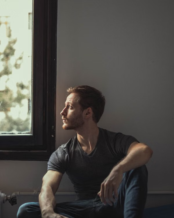 man sitting by a window reflecting during a mental health and ketamine therapy journey