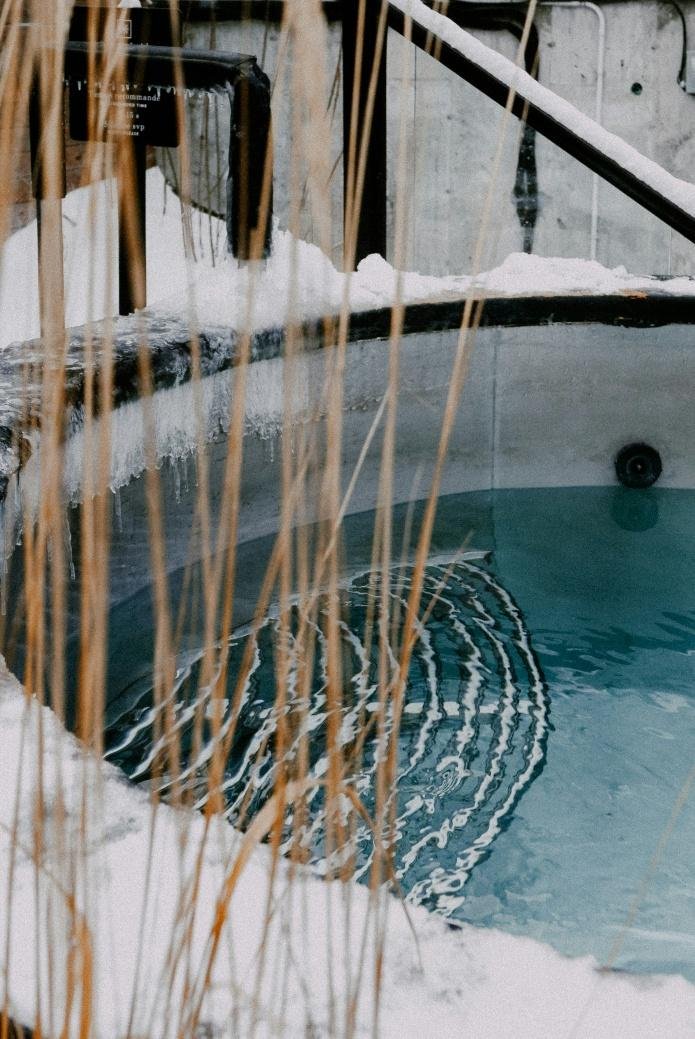 A hot tub outdoors with snow covering the surrounding ground