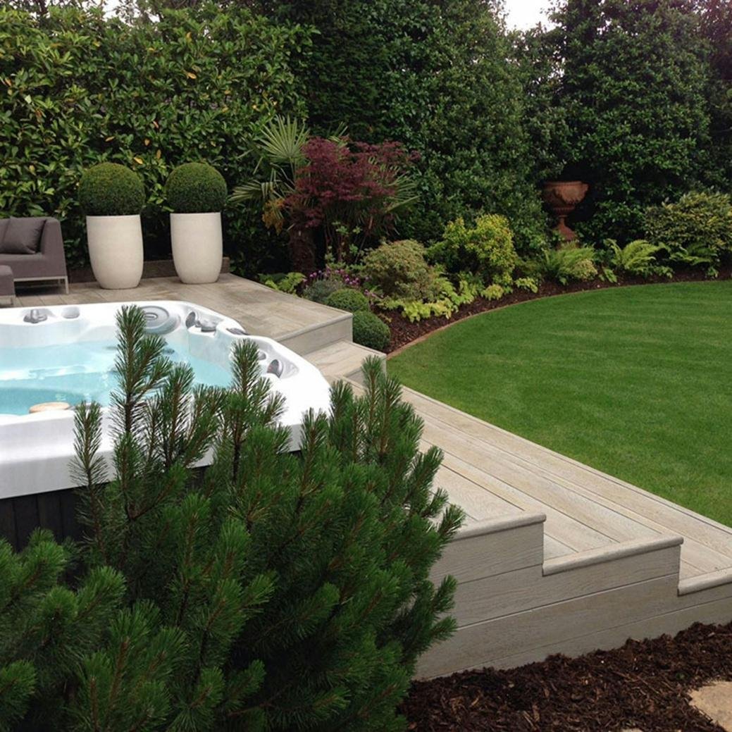 Lush green plants in a backyard with a hot tub
