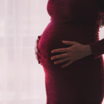 A pregnant person holding their baby bump
